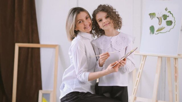 Happy mother and daughter sitting together and hugging in art studio. mother's day concept 