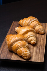 Fresh croissants on a wooden board. Freshly baked in morning.