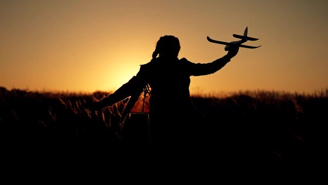 Happy girl with oy in natural park. Child runs on grass with an airplane. Chidhood dream. Happy baby girl with toy airplane at sunset. Child runs on grass in field. Dream travel concept