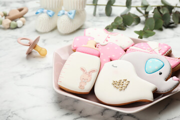 Plate of baby shower cookies and accessories on white marble table, closeup