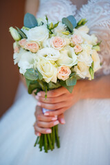 Hands of the bride close-up with a bouquet of fresh beautiful flowers. Attribute of the bride