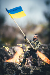 soldado ucraniano ondeando la bandera victoriosa entre llamas frente al invasor ruso - obrazy, fototapety, plakaty