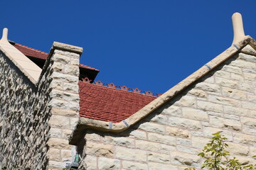 Stone building exterior facade with red clay tile roof with blue sky background