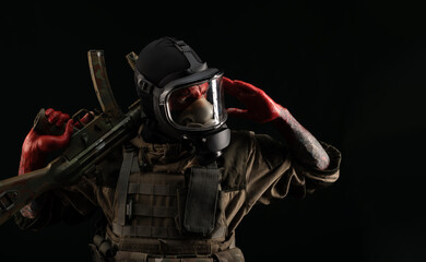 a man in a military uniform and a gas mask holds a weapon with bloody hands with an angry...