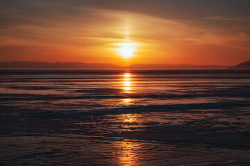 Fototapeta na wymiar sunset over the lake Baikal. Listvyanka, Russia, february 2022.
