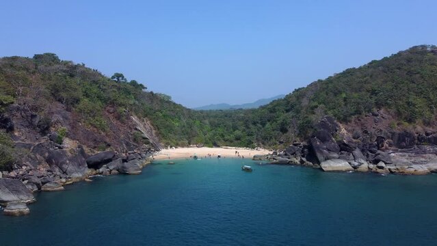 Beautiful secret beach Butterfly in Goa, India. Aerial view of pristine beach with rocky bay and waves crashing.