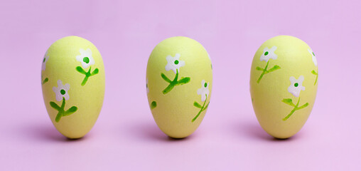 Three yellow Easter eggs on a pink background