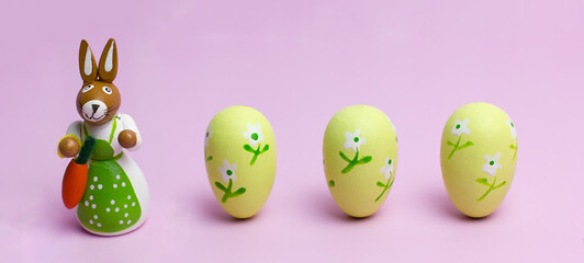 Easter mom rabbit and three eggs on a pink background