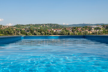 Fototapeta na wymiar Empty Swimming pool with beautiful city view of Novi Sad, Serbia. Luxury summer vacation concept.