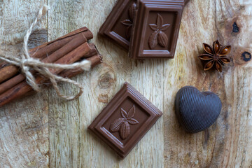 Chopped chocolate cubes, cinnamon stick and star anise on a dark background.