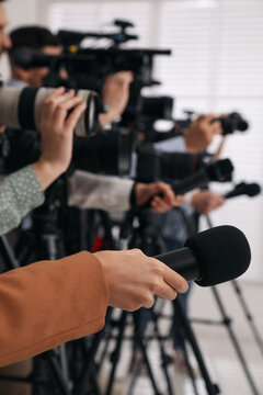 Group of journalists with cameras waiting for official person indoors, closeup