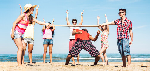 Multicultural friends group having fun together with limbo game at beach vacation - Summer joy life...