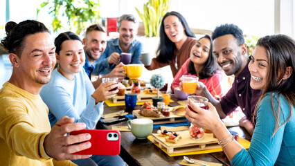 Friends taking selfie on breakfast time drinking juices and eating cakes - People having fun at fashion cafeteria - Life style concept with happy men and women at cafe bar - Selective focus on sides