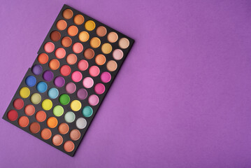 An eye shadow palette on a purple background. Top view, flat lay. 