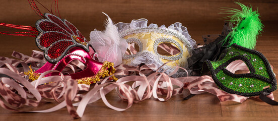Carnival masks, beautiful venetian masks in detail with serpentine on a table, selective focus.