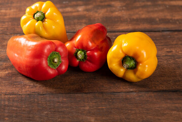 Red and yellow peppers over rustic wood, black background, selective focus.
