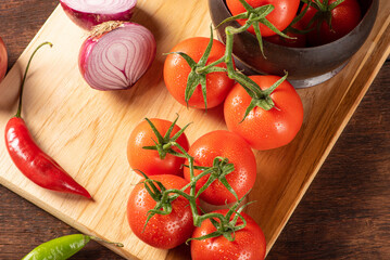 Table with red and yellow peppers, peppers, onions and garlic and tomatoes, over rustic wood, black background, top view.