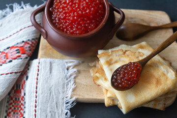 Still life. Maslenitsa week. A pack of Russian pancakes with red caviar in a rustic style, close-up.