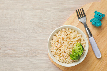 Bowl with tasty pasta and broccoli on white wooden table, top view. Space for text