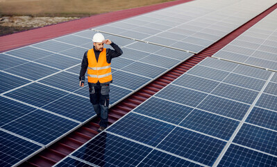 A worker going around rooftop and checking on solar panels.
