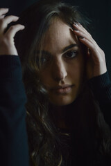 Fototapeta premium Portrait of a beautiful young woman who tries to hide her face with her hand and go unnoticed