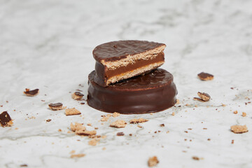 Dark chocolate and dulce de leche alfajores on a marble table.