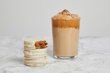 Coffee frappé, cold caramel coffee with white alfajores with dulce de leche on a marble table