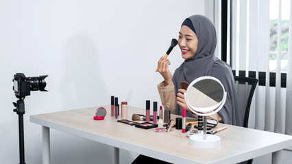 Asian muslim woman beauty blogger holding makeup brush and applies to review how to use makeup brush