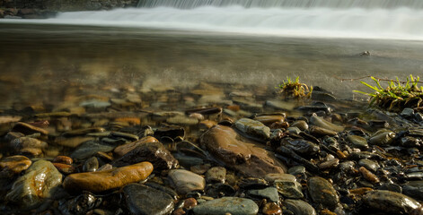 Selective focus shot of pebbles against a waterfall