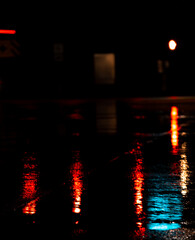 Vertical shot of the red lights reflected on the wet ground during rain at night