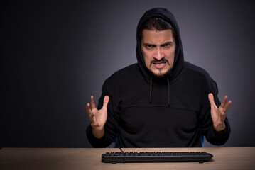 Young male hacker on grey background