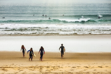 Group of surfers running towards water. Costa Caparica, Lisboa, Portugal.
