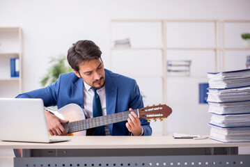 Young male employee playing guitar at workplace