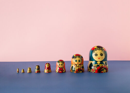 Russian dolls matryoshka or babushka stacked on a pink and blue background. Minimal concept.