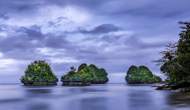 Distant view of the beautiful islets in the glassy water on a cloudy day in Philippines