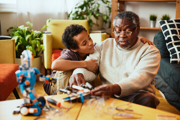 Obraz premium A grandfather showing his grandchild how to make a robot while sitting at home.