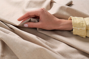 Woman touching soft beige fabric, closeup view