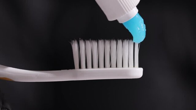 A closeup shot of a toothbrush with a strip of blue toothpaste.