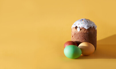 Close-up of colored Easter eggs and kulich on a yellow background. With a space to copy. High quality photo