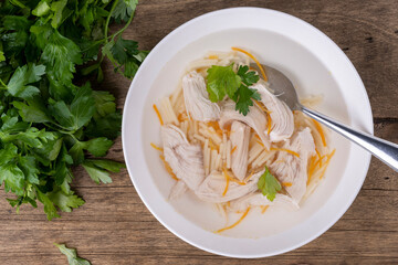 chicken broth in a white plate on a wooden background