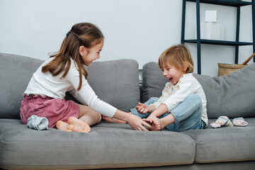 Happy girl tickling boy's foot, they both heartedly laugh.