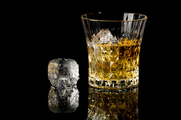 whiskey and ice with reflection on a black background