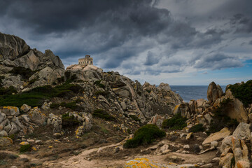 Fototapeta na wymiar l'ancien semaphore de Capo Testa en Sardaigne qui servait de phare au milieu des roches de granit sous un ciel d'orage