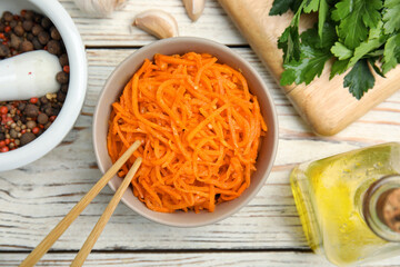 Delicious Korean carrot salad, oil, spices and parsley on white wooden table, flat lay