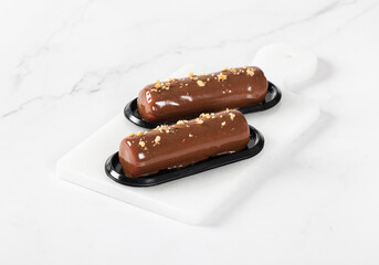 Dessert without baking. Vegan Chocolate nut cake t in the form of a bar, with mirror glaze on a serving board. Light background