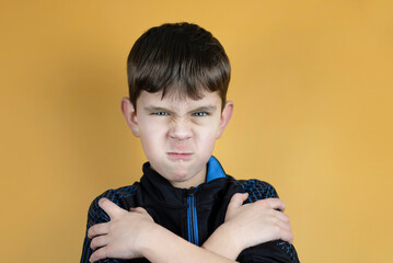 Portrait of a boy 6-8 years on an orange background, the boy is angry and sad about his parents, he...