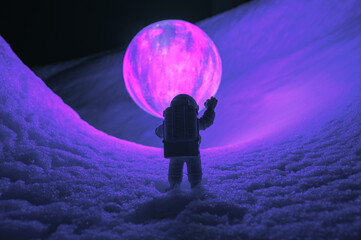 Silhouette of the toy of astronaut against levitating glowing sphere over surface icy planet...