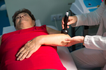 Old woman suffering from rheumatism getting physical therapy from physiotherapist in the clinic