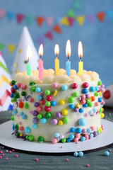 Cute bento cake with tasty cream and burning candles on light blue wooden table