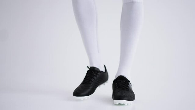 young afro-american football player is playing with ball in studio, closeup of feet and full-length